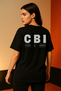 Person wearing a black t-shirt with 'CBI' text on the back against a warm-toned wall.